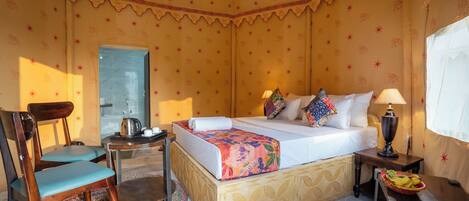 A room with a bed, a chair, a table, and a lamp.