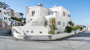 Ein weißes Gebäude mit einer gewölbten Fassade, einer kleinen Palme und blauem Himmel.