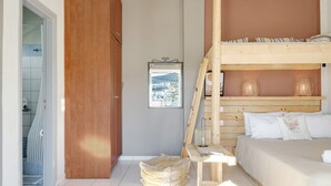 Ein Schlafzimmer mit Etagenbett, Holz-Kopfteil, einem gerahmten Bild an der Wand und Blick auf eine Stadt durch ein Fenster.