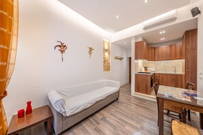 Quarto moderno com sofá, uma mesinha, cozinha compacta e armários de madeira.