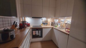 A compact kitchen with a built-in oven, a coffee maker, and a kettle on the counter. - Cozy 3-room vacation apartment at Dresden main station  (Dresden)