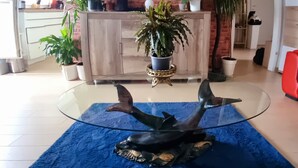 A living room with a glass coffee table, a blue rug, and a brick wall. There are potted plants on the coffee table and a flat-screen TV mounted on the wall. - Cozy 3-room vacation apartment at Dresden main station  (Dresden)