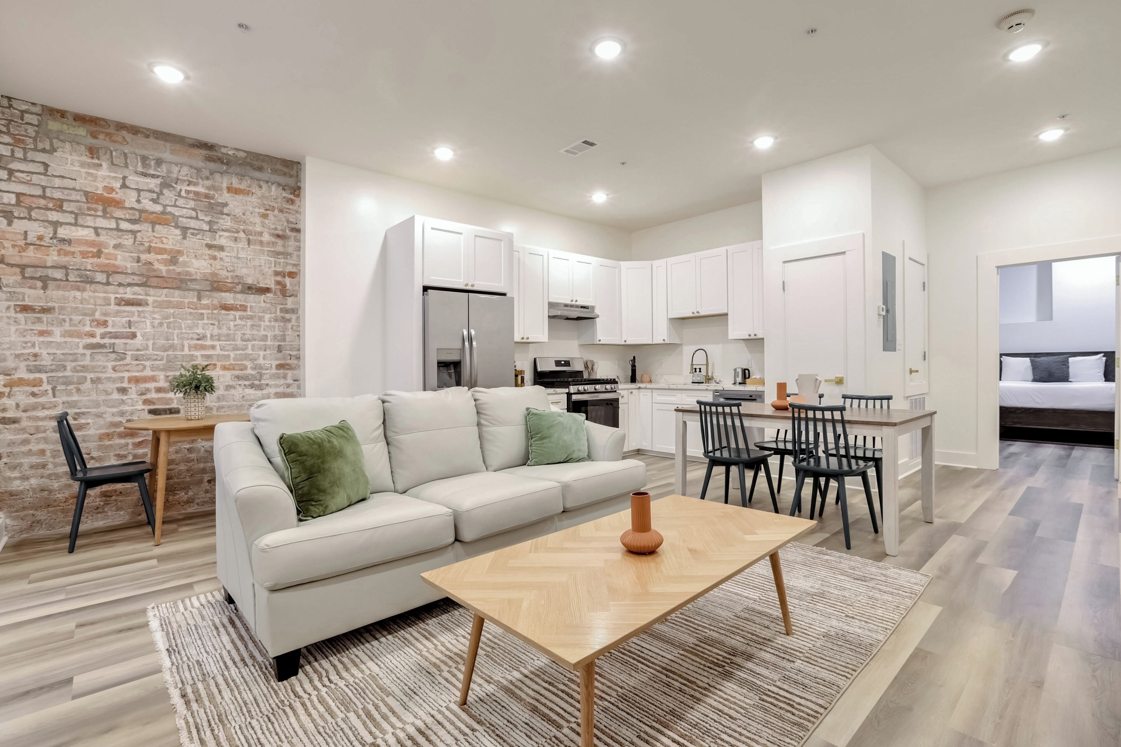 A modern apartment with a living room, dining area, kitchen, and a bedroom.