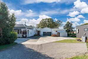 A two-story house with a garage, a covered porch, and a gravel driveway.