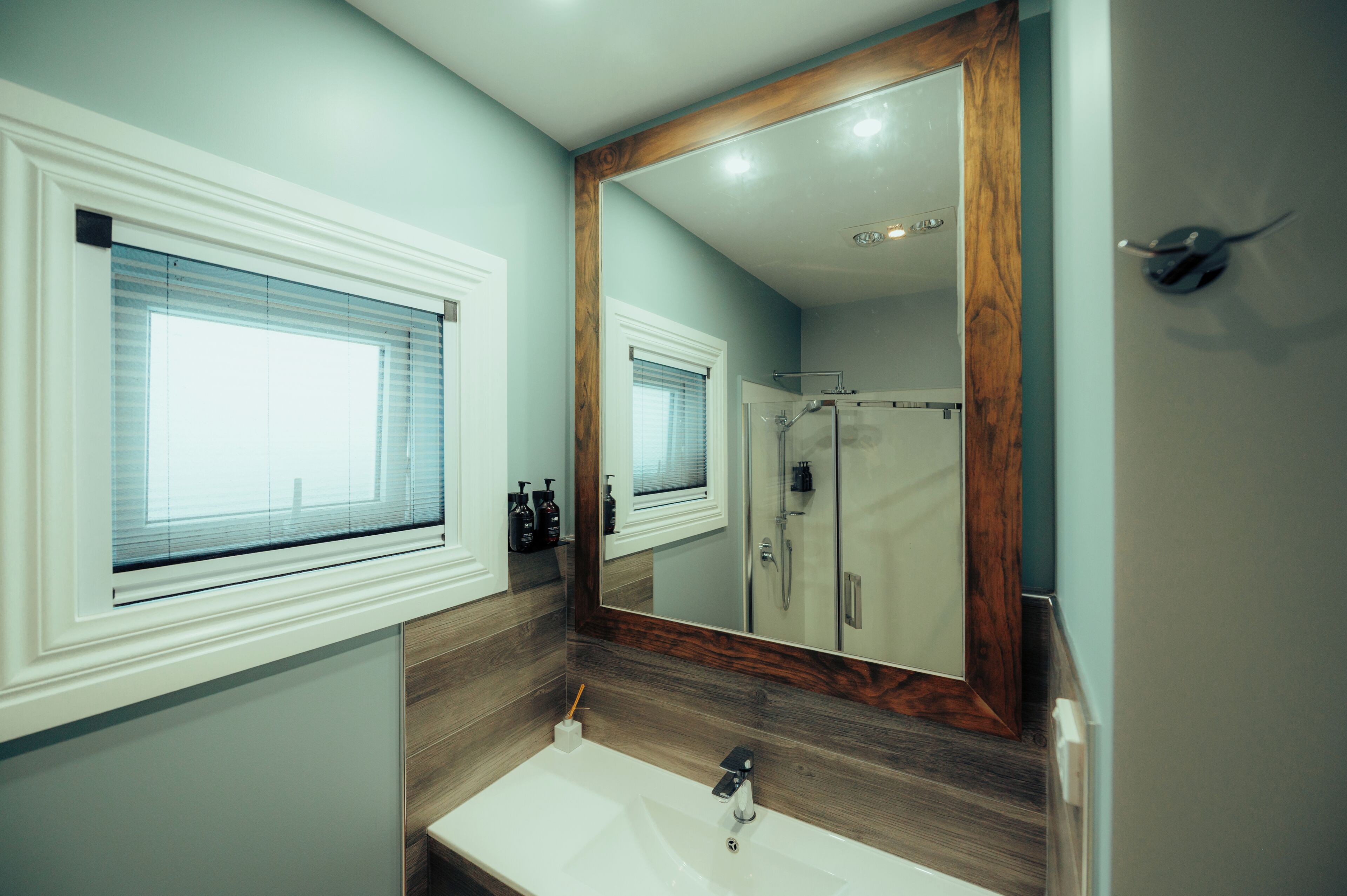 A bathroom with a large mirror, a sink, and a shower.