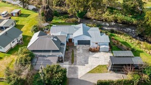 An aerial view of a residential property with multiple buildings, a driveway, and a river. - Two Rivers Boutique Lodge Ohakune (Ohakune)
