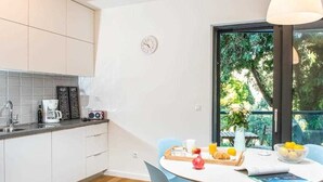 A modern kitchen with white cabinets, a coffee maker, and a dining area with a round table and blue chairs.