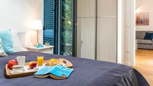 A hotel room with a bed, breakfast tray, and a view of the outdoors.