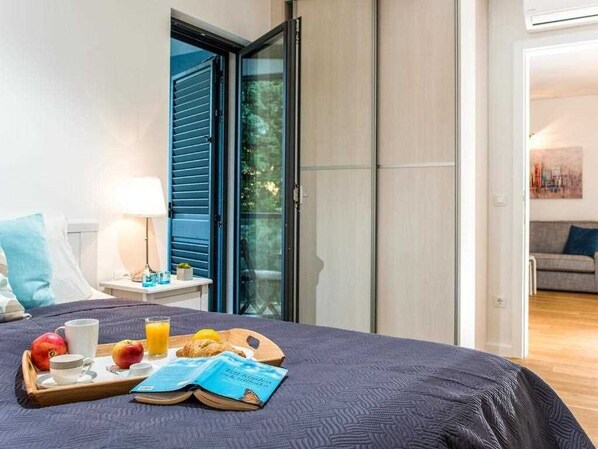 Habitación de hotel con cama, bandeja de desayuno y vistas al exterior.