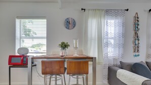 A living room with a dining area, a sofa, a clock, and a microwave.