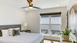 A bedroom with a bed, a nightstand, a lamp, a ceiling fan, a window, and a plant on a side table. - Lakefront Home w/ Dock & Patio in San Angelo! (San Angelo)