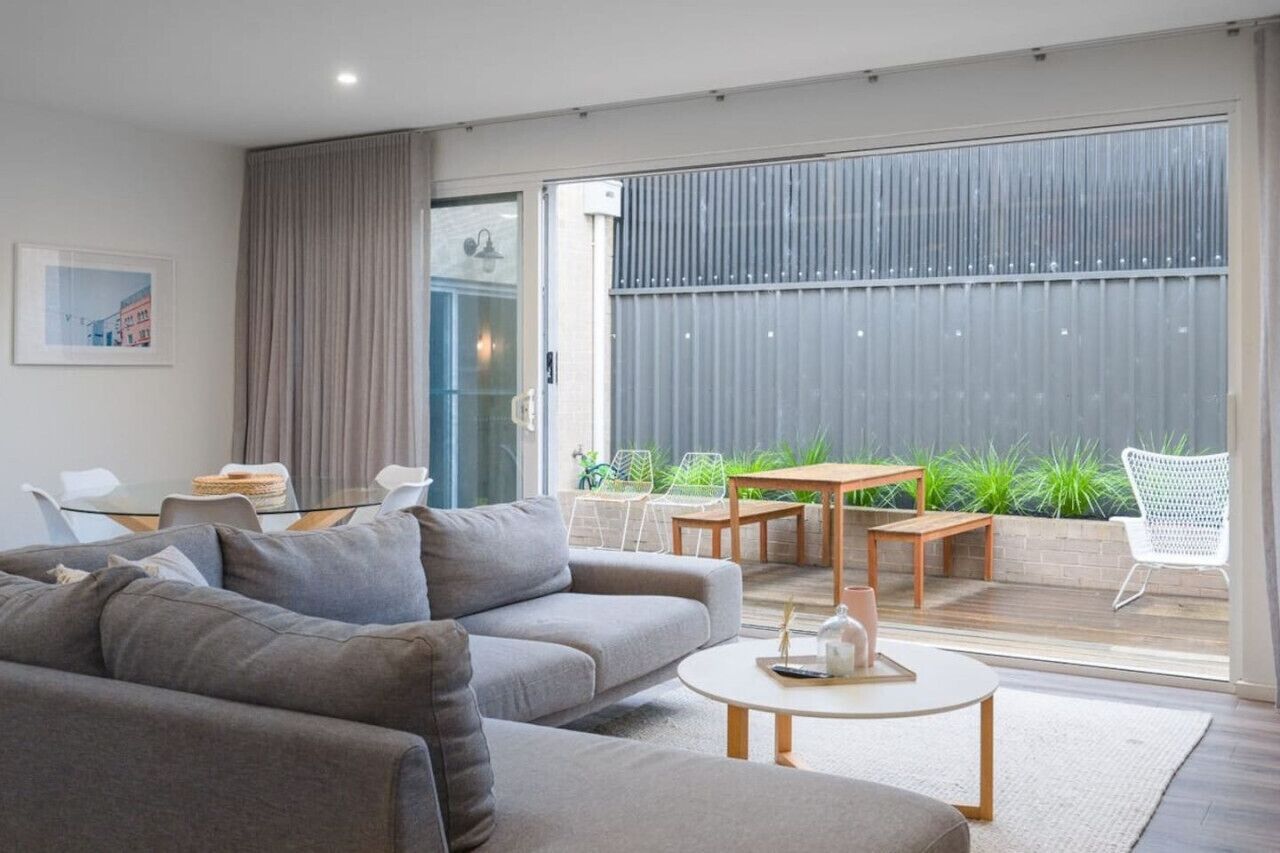 A modern living room with a grey sofa, a round coffee table, and a dining area with a table and chairs.
