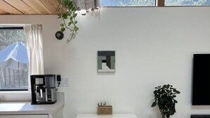 Een moderne keuken met witte kasten, een koffieapparaat en een eethoek met een witte tafel en stoelen.
