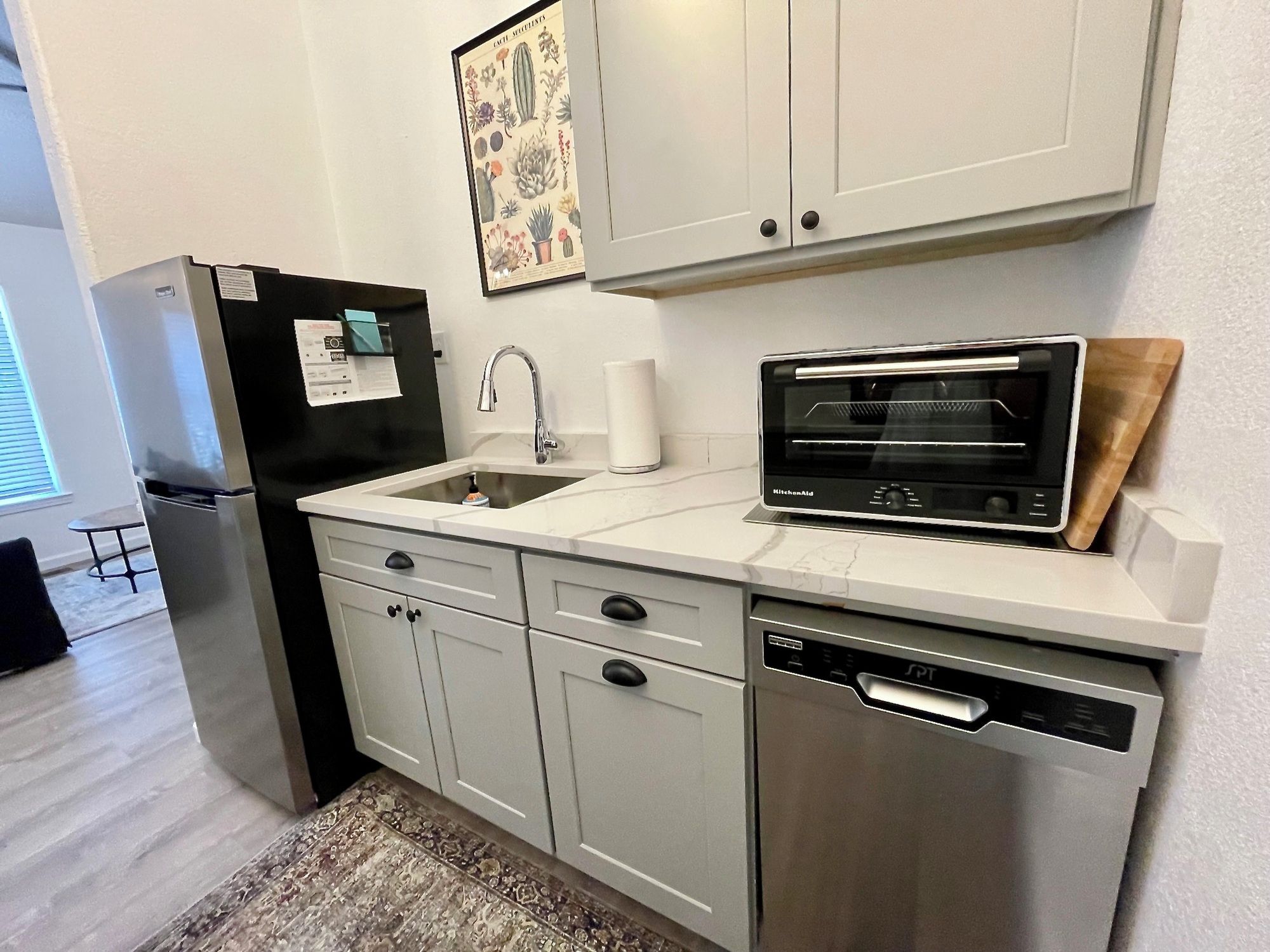 A modern kitchen with a refrigerator, sink, dishwasher, and a built-in oven.