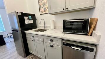 A modern kitchen with a refrigerator, sink, dishwasher, and a built-in oven.