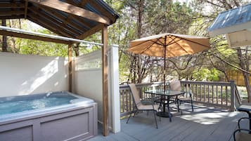 A deck with a hot tub, outdoor seating, and a pergola.