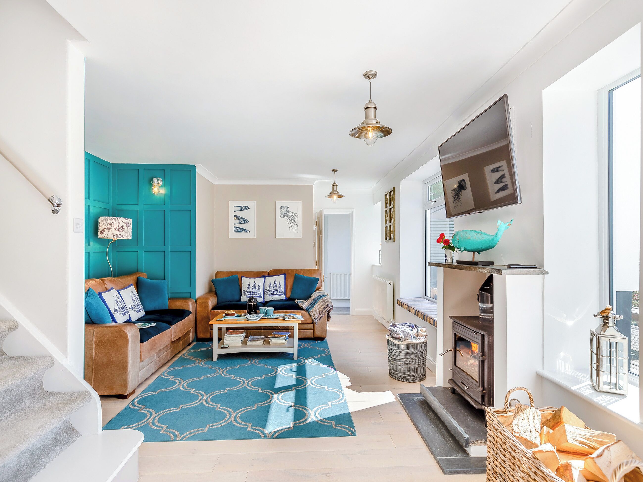 Un salon moderne avec une cheminée, un mur d’accent de couleur turquoise et un tapis à motifs.
