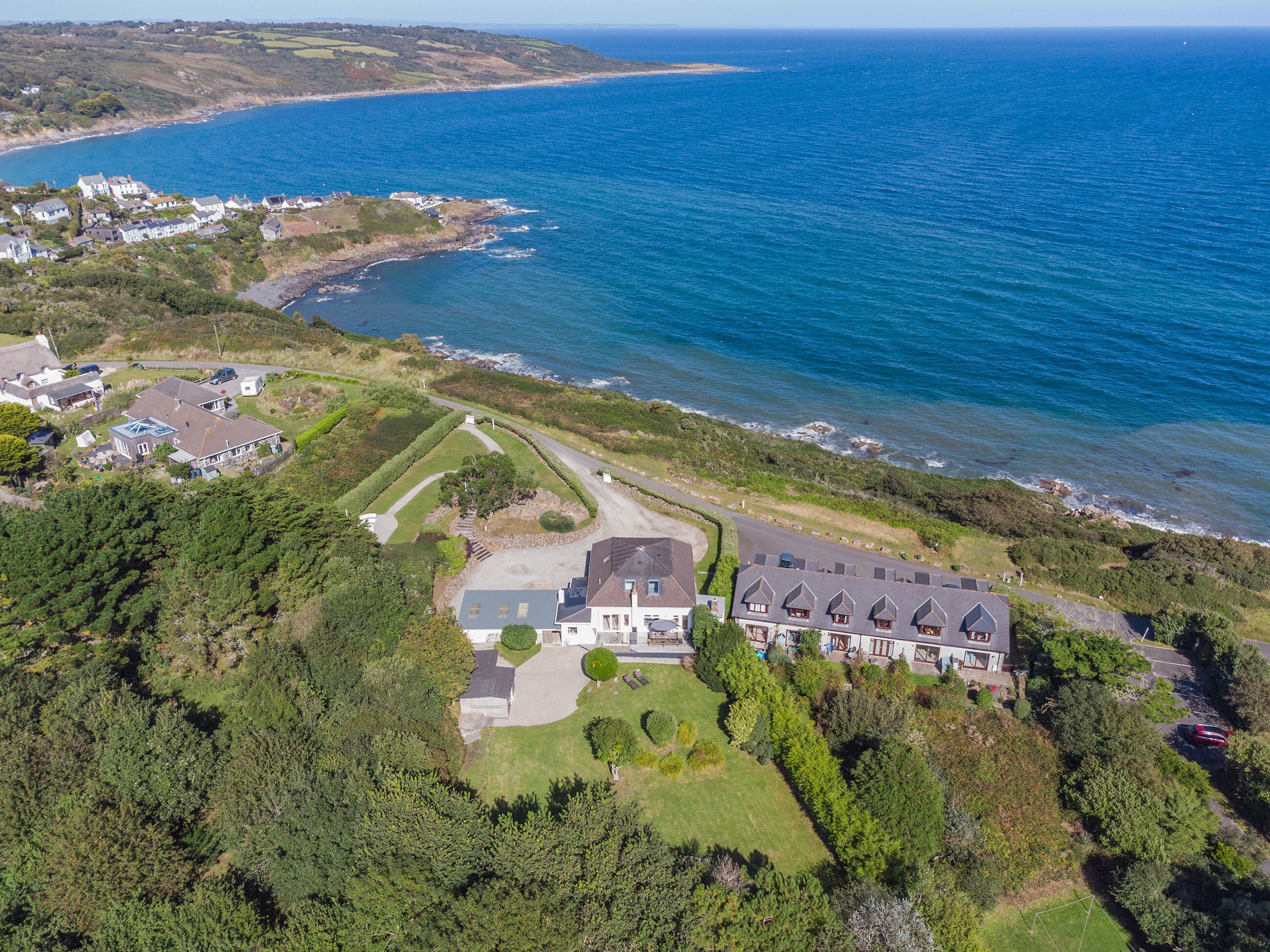 A coastal property with a large house, a driveway, and a well-maintained lawn.