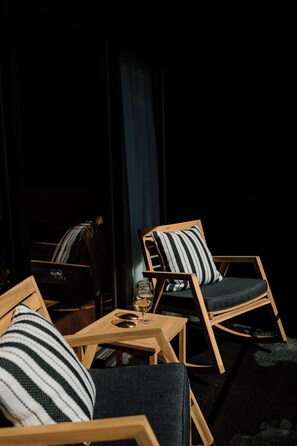 Una habitación oscura con muebles de madera, incluyendo una silla y una mesa con un vaso.