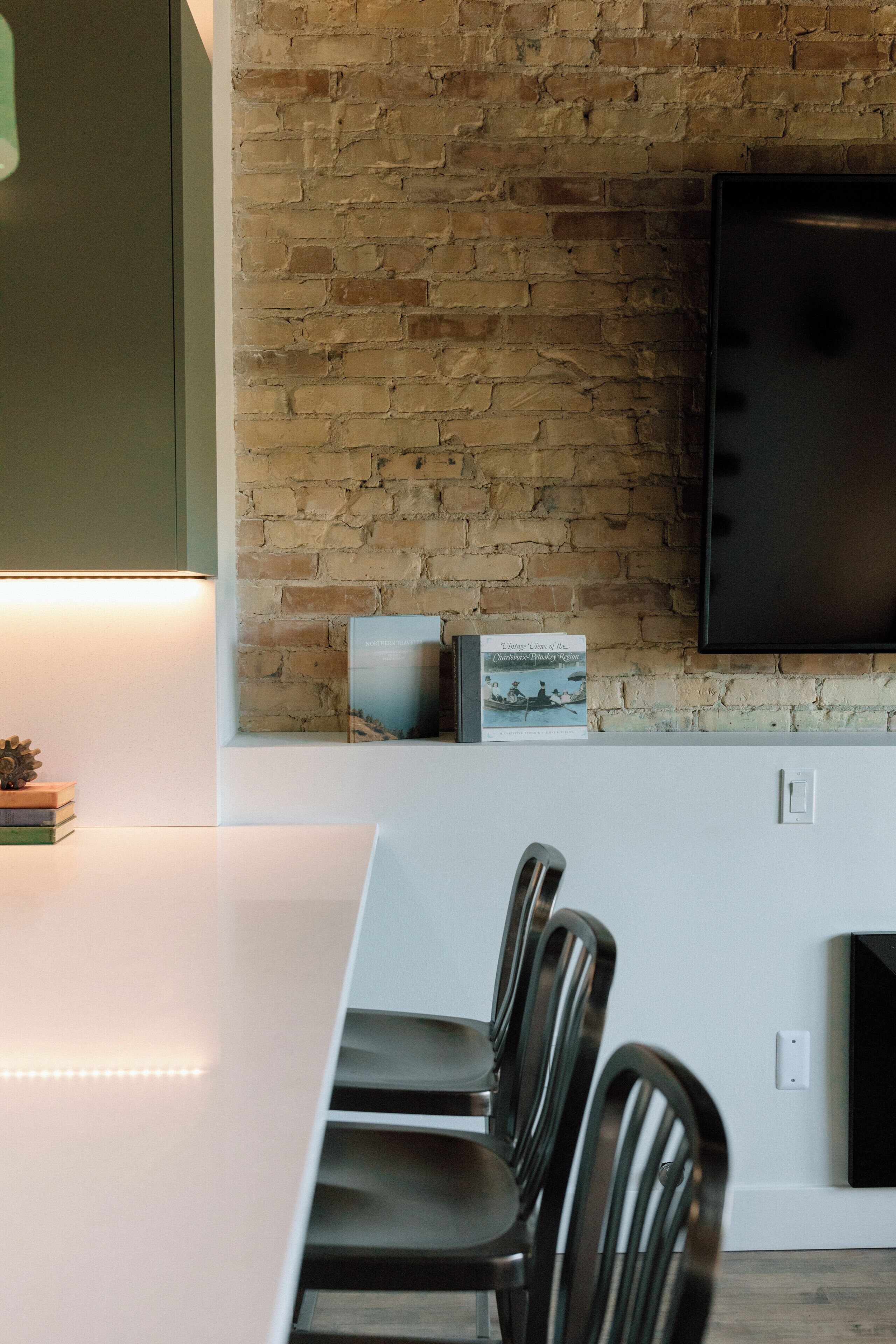Una cocina moderna con pared de ladrillo, un televisor de pantalla plana y una zona de comedor con sillas y una mesa.