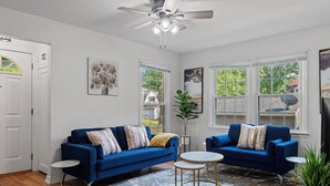 A spacious living room with two blue sofas, a ceiling fan, and large windows. - Tranquil 3-bedroom house with a massage chair  (Springfield)