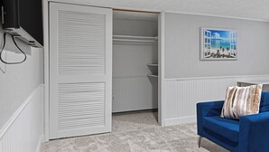 A room with a blue sofa, a white closet with louvered doors, and a framed picture on the wall. - Tranquil 3-bedroom house with a massage chair  (Springfield)