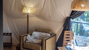 Una habitación con tienda de campaña acogedora, con cama, lámpara y una mesa con vela.