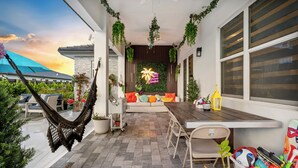 Un patio exterior moderno con una hamaca, zona de estar y plantas en macetas.