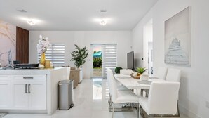 Un espacio de sala moderno y bien iluminado, con cocina, comedor y televisor.