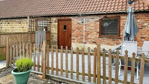 A brick house with a tiled roof, a wooden door, and a window with shutters. - Cooper Cottage - UK47544 (Potto, near Northallerton)
