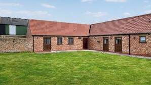 A brick building with a red-tiled roof, a grassy courtyard, and a stone wall. - Cooper Cottage - UK47544 (Potto, near Northallerton)
