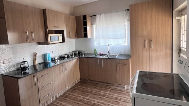 Een moderne keuken met houten kastjes, een magnetron en een fornuis.