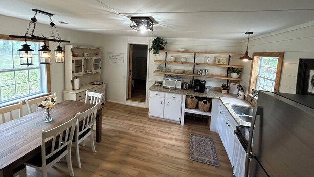 Une cuisine avec des meubles en bois, une table à manger et des luminaires suspendus.