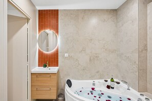 A bathroom with a bathtub, a mirror, a sink, and a wooden cabinet.