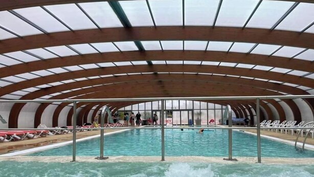 An indoor swimming pool with a curved roof structure and multiple lanes.