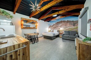 A cozy interior with a kitchen, dining area, and a bed with a mountain view mural. - 19-Hansen Inn & Cabins, Cabin Suite, 1 King, 1 Queen, Sleeper Sofa, Dog Friendly (Wall)