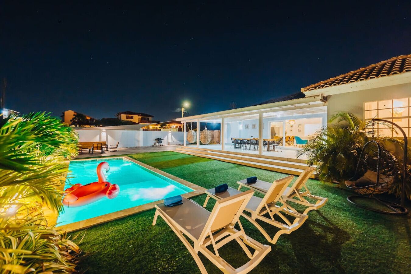 Un cortile con piscina, area salotto all'aperto e patio coperto.