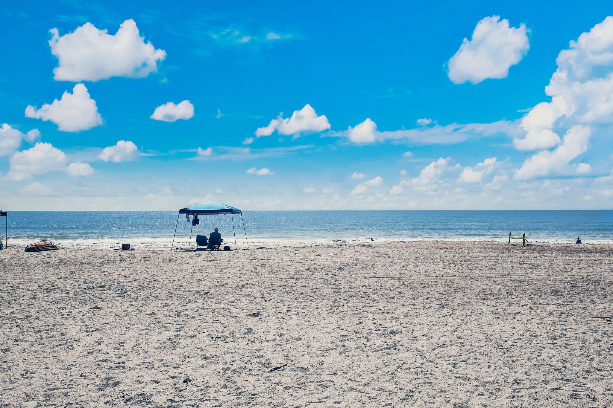 A beach with a covered seating area and a volleyball net.