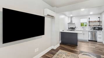 A modern kitchen with white cabinets, a central island, and a built-in microwave.