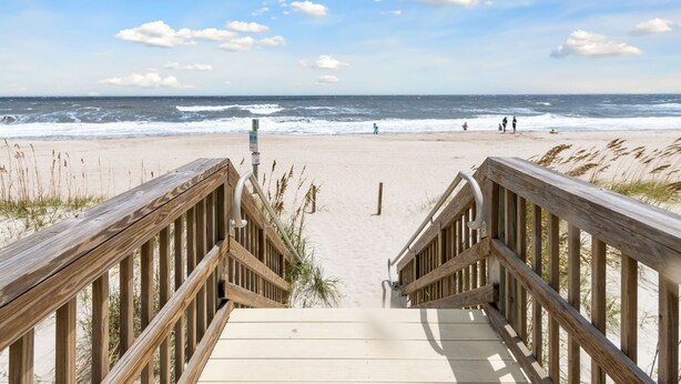 A wooden boardwalk leading to a beach with waves and people in the distance. - Beach 5 Villas - Immaculate 300 steps from the Ocean (Fernandina Beach)