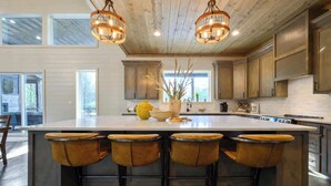 A spacious kitchen with a large island, bar stools, and pendant lighting. - Pets | Heated Pool | Game Room | Sleeps 36 (Broken Bow)
