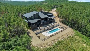 A modern house with a pool, surrounded by dense forest.