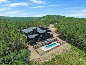 A modern house with a pool, surrounded by dense forest. - Pets | Views | Heated Pool | Games | Sleeps 26 (Broken Bow)