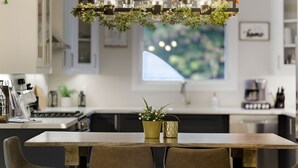 Una cocina moderna con una mesa de comedor, sillas, una araña con velas y un ventanal con vistas.
