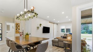 Una cocina moderna con una mesa de comedor de madera, taburetes de bar y una lámpara colgante.