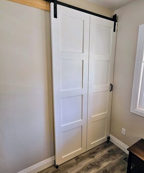 A room with a sliding door, a window, and a wooden floor.