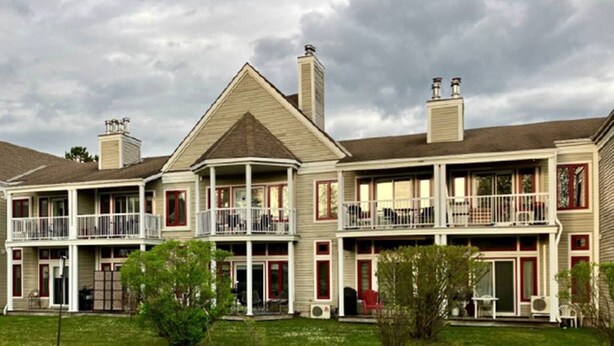 A two-story building with a central balcony, multiple windows, and a chimney.