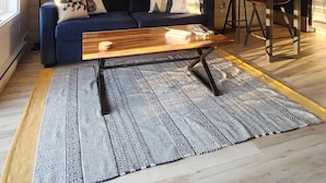 A modern living room with a blue sofa, a wooden coffee table, and a patterned rug.