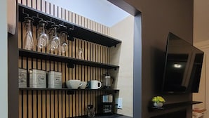 A modern kitchen with a built-in microwave, a coffee maker, and a flat-screen TV mounted on the wall.