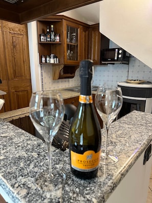 A kitchen counter with a bottle of Prosecco Treviso and two wine glasses. - Casa Marie, a rustic natural stone home with a lake view and a rooftop terrace (Vercana)